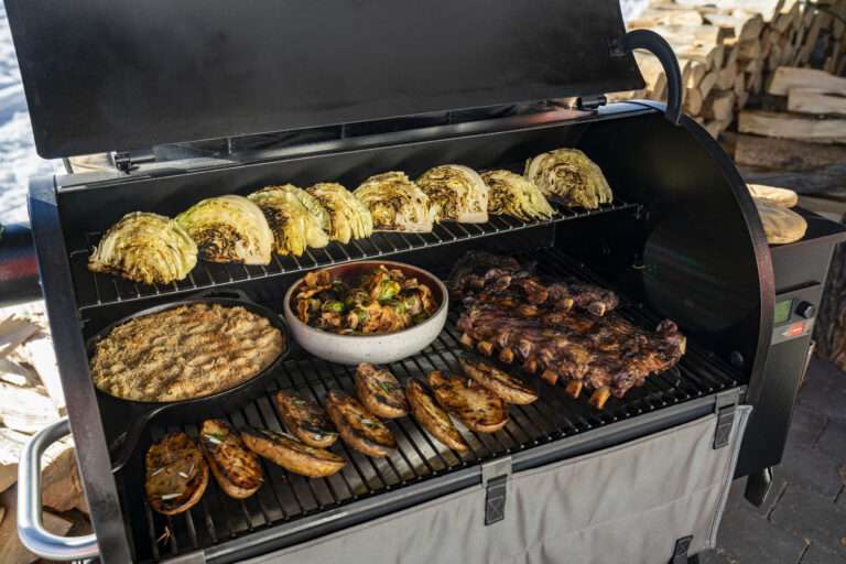 traeger grill open in winter, laden with grilled food
